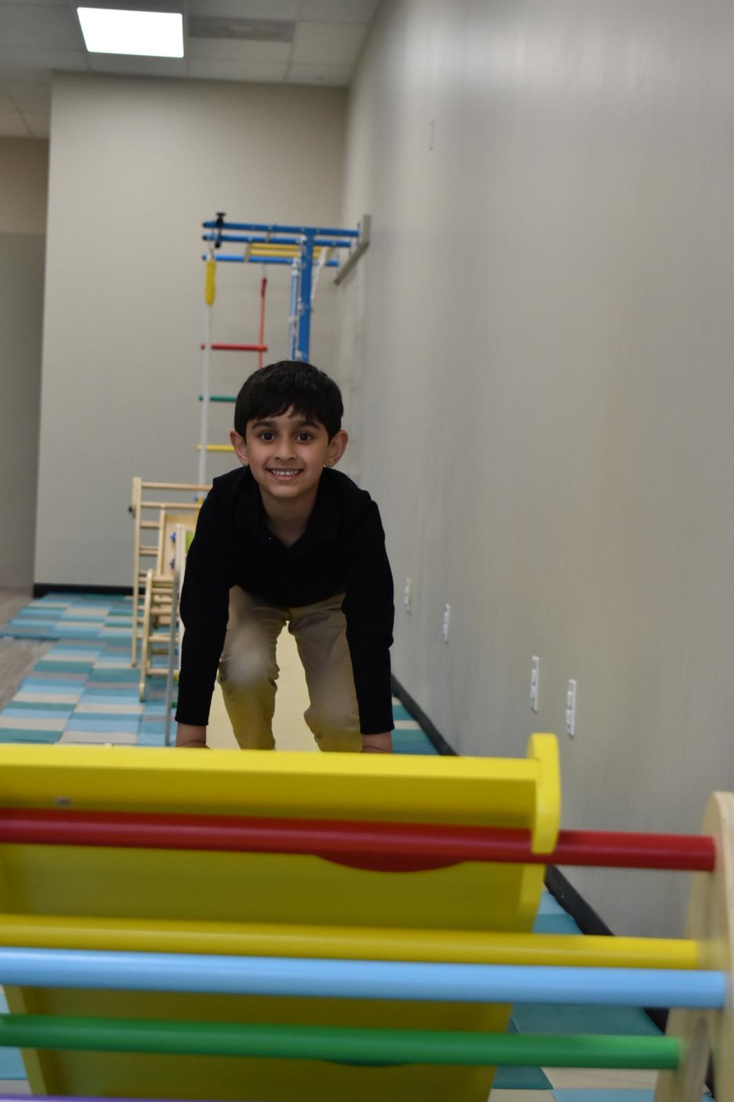 Child sitting atop a large digging machine, gleefully scooping large amounts of sand. 